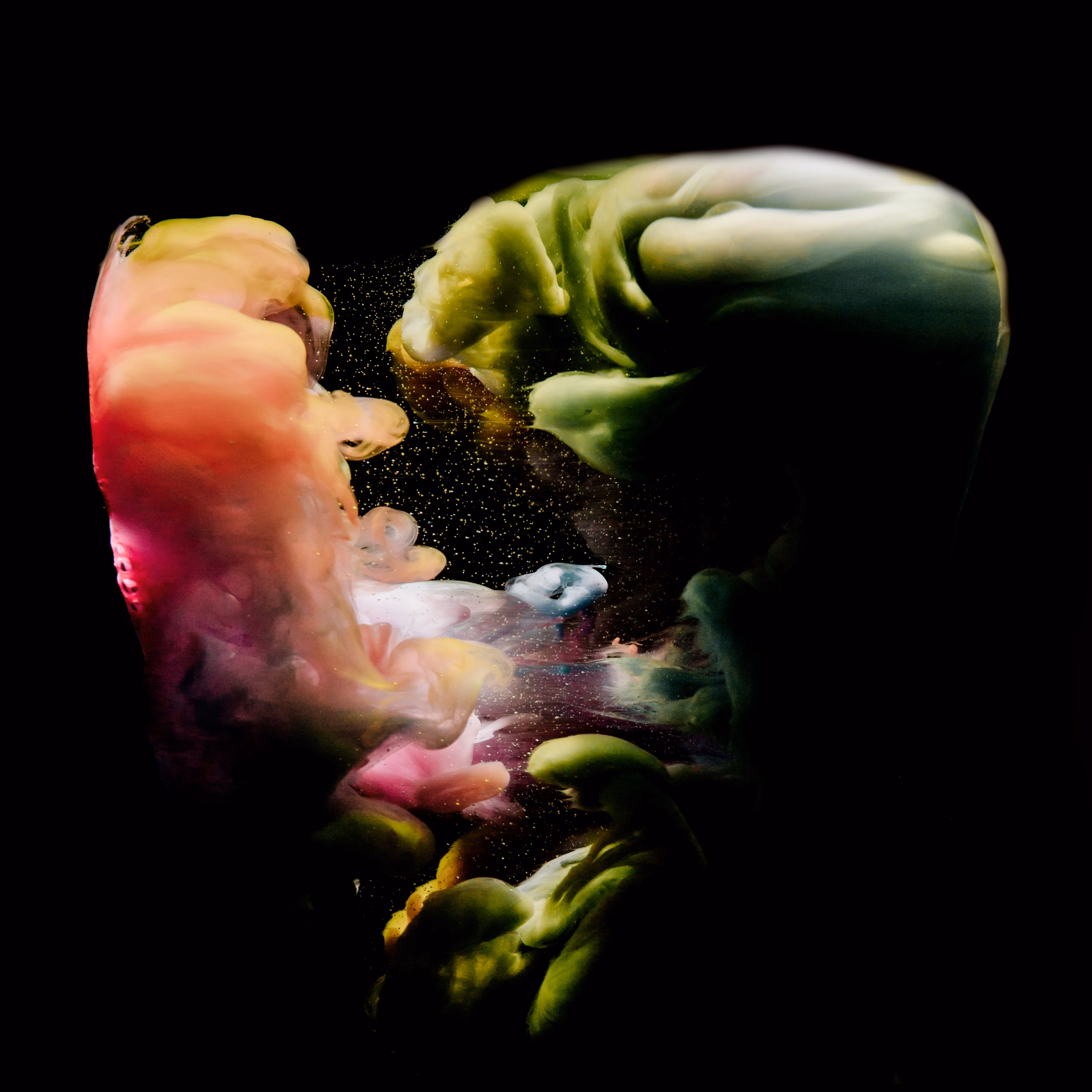 Abstract colorful clouds of liquid pigments swirling in dark space, with green, yellow, and pink smoke-like forms resembling an animated cosmic nebula.