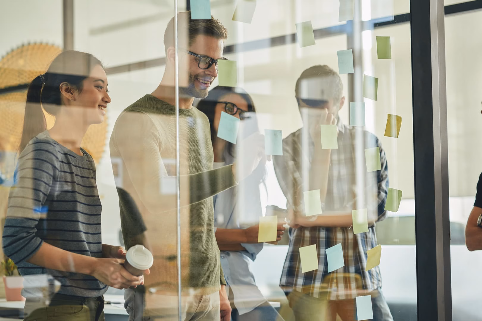 Team brainstorming with sticky notes on glass wall during creative planning session